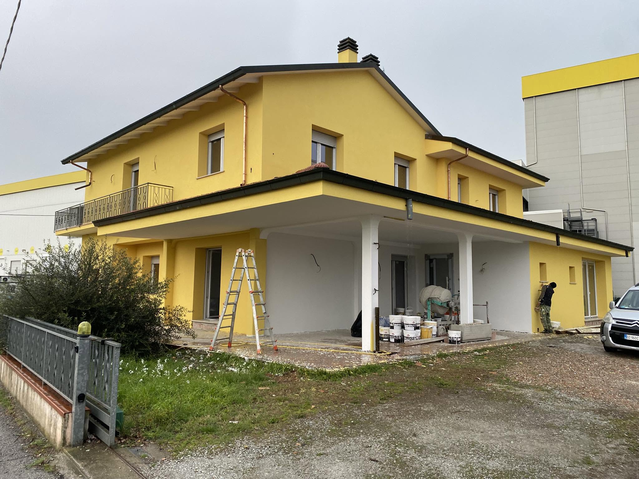 Villa bifamiliare tinteggiata di giallo con portico bianco